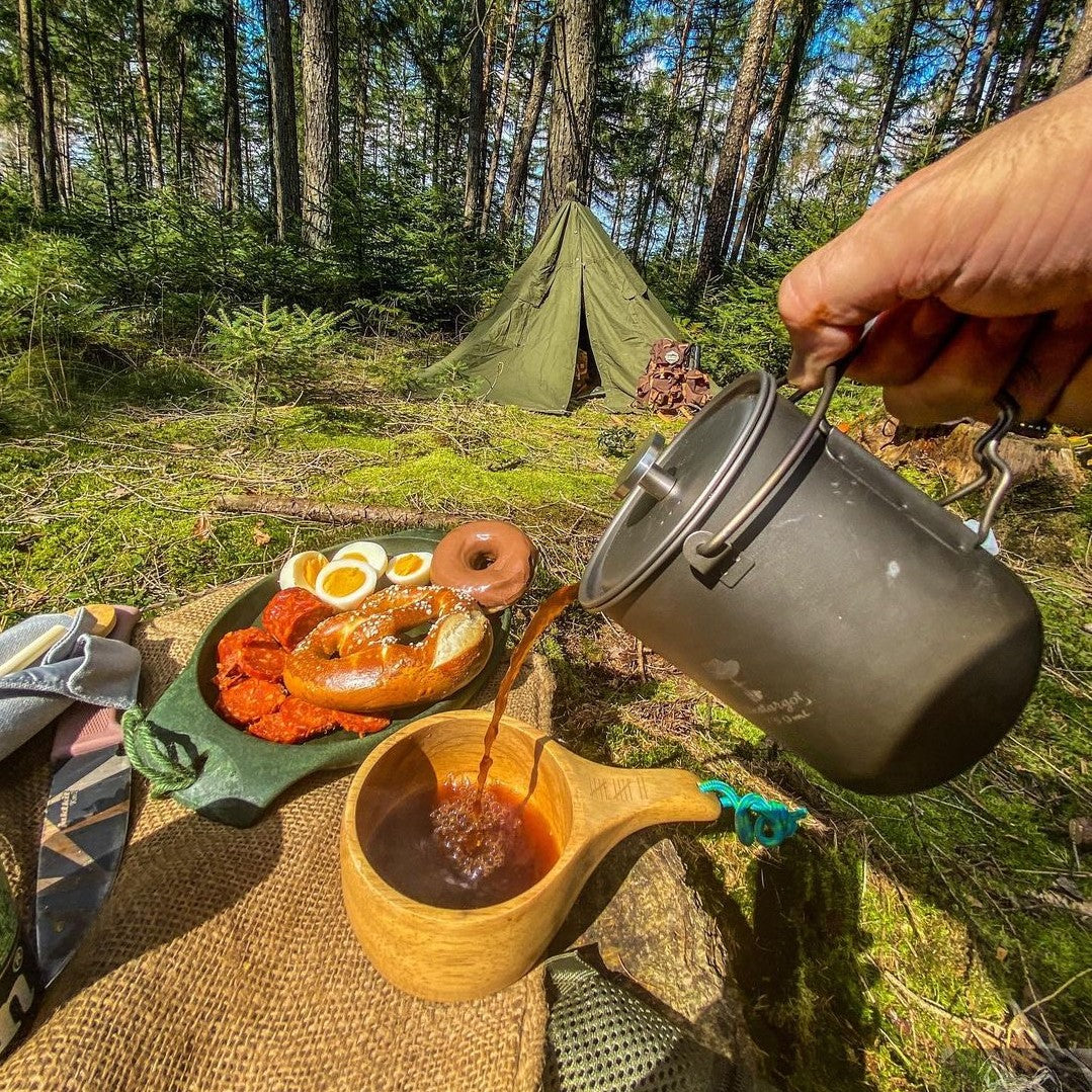 A man uses a bestargot titanium french press to make coffee in a campsite